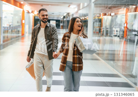 In the mall with clothes. Young couple are in supermarket together In the mall with clothes. Young couple are in supermarket together 131346065