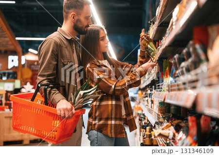 Oil in hands. Young couple are in supermarket together 131346109