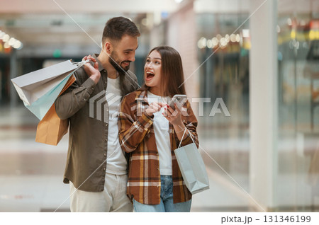 Excited people with smartphone. Young couple are in supermarket together 131346199