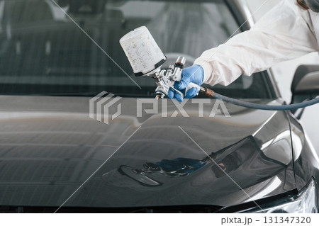 Close up view of man that is painting a car by using spray guy Close up view of man that is painting a car by using spray guy 131347320