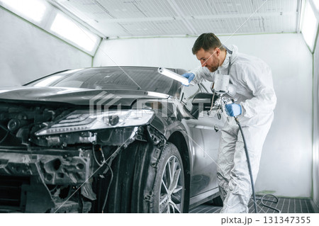 Professional worker. Man is painting a car by using spray guy 131347355