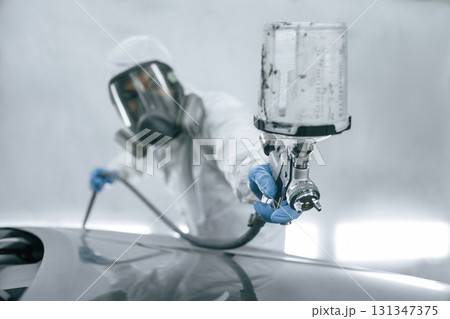 Close up view of man that is painting a car by using spray guy Close up view of man that is painting a car by using spray guy 131347375