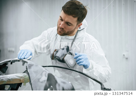 Unfinished part. Repairman is working with carcass of the car in the garage Unfinished part. Repairman is working with carcass of the car in the garage 131347514