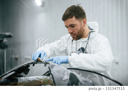 Unfinished part. Repairman is working with carcass of the car in the garage Unfinished part. Repairman is working with carcass of the car in the garage 131347515