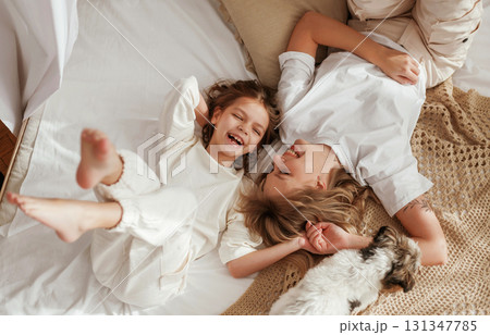 View from the top, lying down on bed. Mother with daughter are at home together 131347785