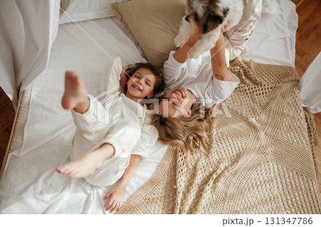 View from the top, lying down on bed. Mother with daughter are at home together 131347786