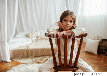 Sitting on the chair. Cute little girl is at home Sitting on the chair. Cute little girl is at home 131347788