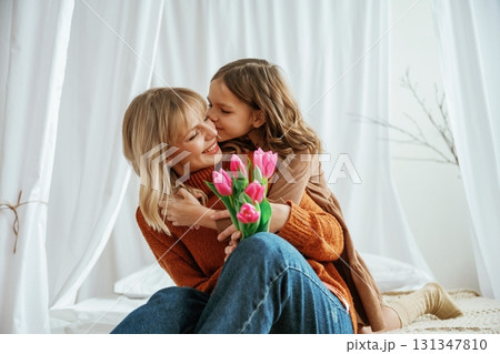 Flowers in hands. Mother's day concept. Female parent with daughter is at home Flowers in hands. Mother's day concept. Female parent with daughter is at home 131347810