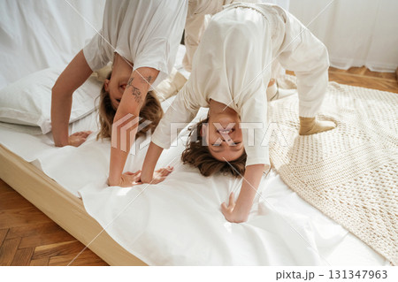 Playing in bed, standing on hands and legs. Mother with daughter are at home together 131347963