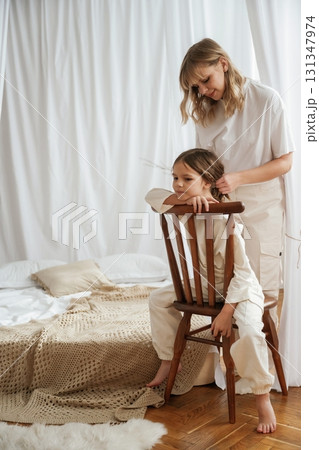 On the wooden chair. Mother with daughter are at home together On the wooden chair. Mother with daughter are at home together 131347974