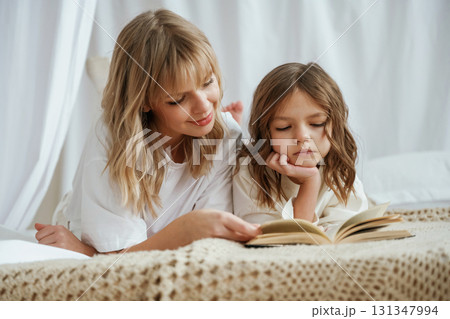 Reading the book together. Mother with daughter are at home Reading the book together. Mother with daughter are at home 131347994