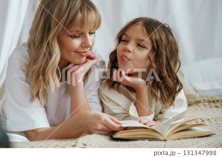 Reading the book together. Mother with daughter are at home Reading the book together. Mother with daughter are at home 131347998