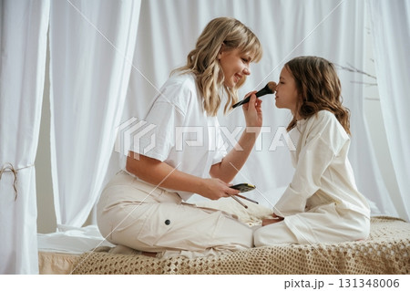 Beauty make up procedure with brush. Mother with daughter are at home together Beauty make up procedure with brush. Mother with daughter are at home together 131348006