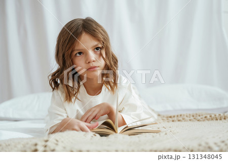 Lying down on the bed with book. Cute little girl is at home Lying down on the bed with book. Cute little girl is at home 131348045