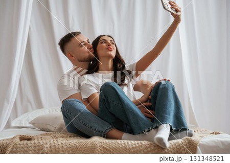 Using smartphone for selfie. Young couple are together at home 131348521