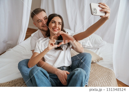 Using smartphone for selfie. Young couple are together at home 131348524