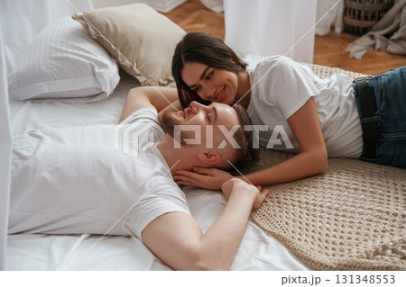 On the bed, lying down and smiling. Young couple are together at home On the bed, lying down and smiling. Young couple are together at home 131348553