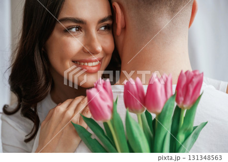 Close up view of woman holding flowers and hugs man. Young couple are together at home 131348563