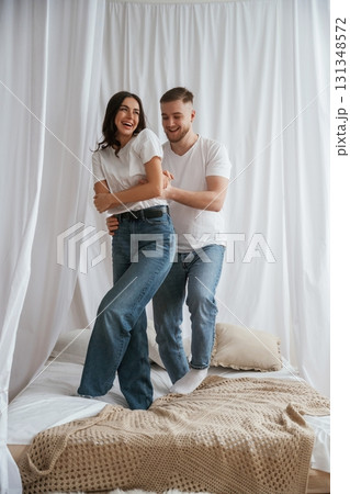 Standing and playing on the bed. Young couple are together at home Standing and playing on the bed. Young couple are together at home 131348572