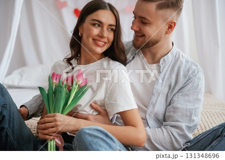 With beautiful flowers in hands. Young couple are together at home 131348696