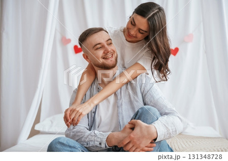 Happy facial expressions, red heart shaped decoration behind. Young couple are together at home Happy facial expressions, red heart shaped decoration behind. Young couple are together at home 131348728