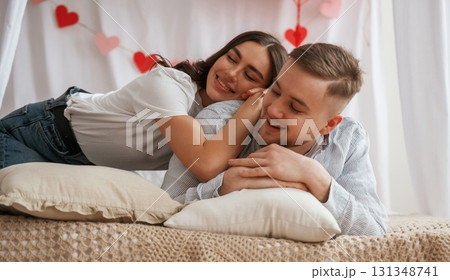 Background with red festive decorations for Valentine's day. Young couple are together at home Background with red festive decorations for Valentine's day. Young couple are together at home 131348741