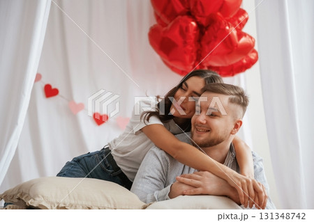 Bunch of heart shaped balloons, celebrating. Young couple are together at home Bunch of heart shaped balloons, celebrating. Young couple are together at home 131348742
