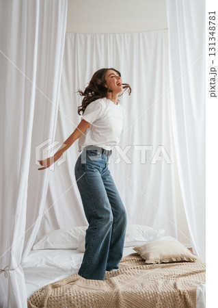 Having fun, jumping. Young beautiful woman is at home on the bed Having fun, jumping. Young beautiful woman is at home on the bed 131348781