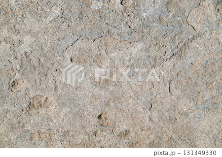 A grey and white stone wall with a lot of holes 131349330