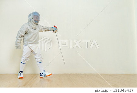 Asian boy with fencing sport uniform hold epee as protect action during practice for the competion. 131349417