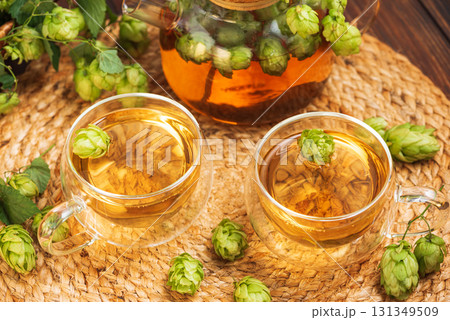 Hop Tea with Fresh Hops in Glass Cups and Teapot on Rustic Background 131349509