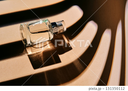 Is the perfume spray bottle lying on a beige background with shadow stripes. Is the perfume spray bottle lying on a beige background with shadow stripes. 131350112