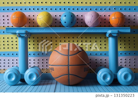 A basketball sits on a blue shelf with other sports balls 131350223