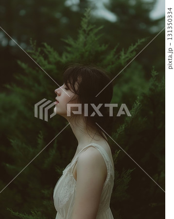 A woman is standing in a forest, looking at the camera 131350334