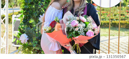 Portraits of student at graduation ceremony with group and family posing outdoors in celebration 131350567