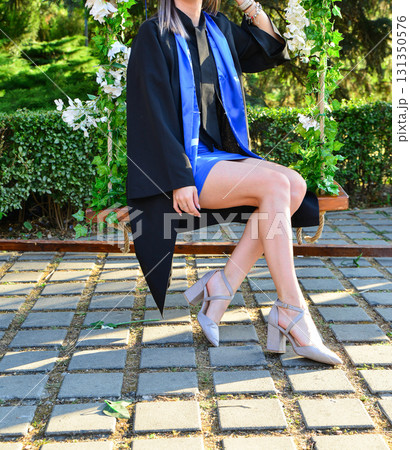 Elegant female student poses proudly in graduation outfit showing beautiful legs and high heels Elegant female student poses proudly in graduation outfit showing beautiful legs and high heels 131350576