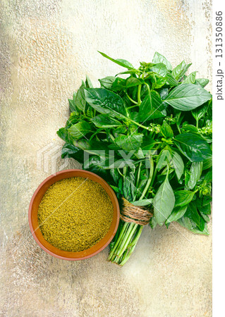 ground green basil, in a ceramic bowl, with a bouquet of fresh green basil, on the table, top view, no people, ground green basil, in a ceramic bowl, with a bouquet of fresh green basil, on the table, top view, no people, 131350886