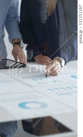 Professional team reviewing financial documents, pointing at charts on desk, collaborating to analyze data and strategize business growth. Business people concept 131351167