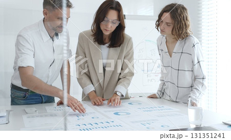 Professional colleagues reviewing financial reports, collaborating on strategic planning in contemporary workspace. Business people concept Professional colleagues reviewing financial reports, collaborating on strategic planning in contemporary workspace. Business people concept 131351241