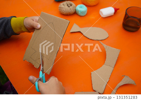 Assemble a fish using cardboard, thread, and paint, with clear instructions, against an orange background. Assemble a fish using cardboard, thread, and paint, with clear instructions, against an orange background. 131351283