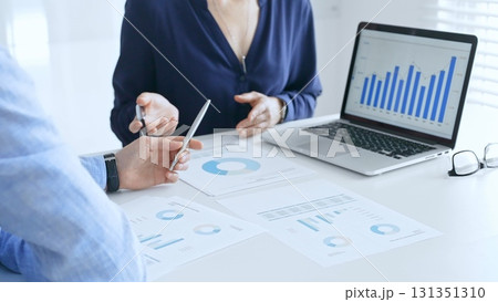 Business professionals collaborating on a laptop, reviewing financial documents, and discussing project strategies in a modern office. Businesspeople in finance concept 131351310