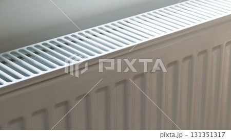 A white heat radiator is installed beneath a window. The fall of the cold weather and the rise in consumer prices. A white heat radiator is installed beneath a window. The fall of the cold weather and the rise in consumer prices. 131351317
