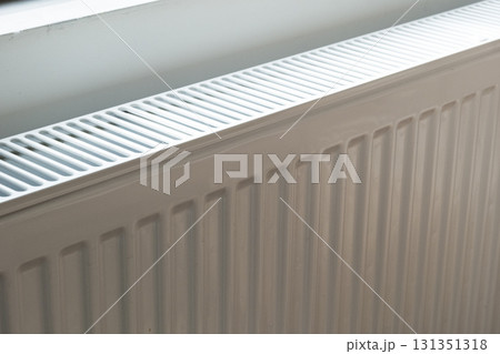 A white heat radiator is installed beneath a window. The fall of the cold weather and the rise in consumer prices. A white heat radiator is installed beneath a window. The fall of the cold weather and the rise in consumer prices. 131351318
