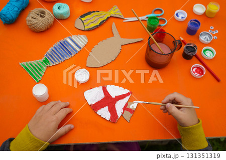 Construct a fish from cardboard, thread, and paint, with step-by-step directions, on an orange background. Construct a fish from cardboard, thread, and paint, with step-by-step directions, on an orange background. 131351319