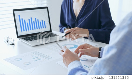Businessman and business woman reviewing financial documents, collaborating over laptop screen, analyzing market charts for strategic corporate planning. Businesspeople and finance concept 131351356