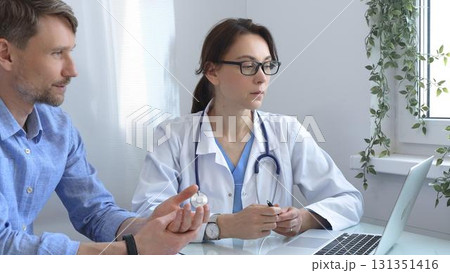 Female doctor consulting with patient in medical office, using laptop to provide healthcare advice and support while discussing treatment options in a professional setting. Medicine concept 131351416