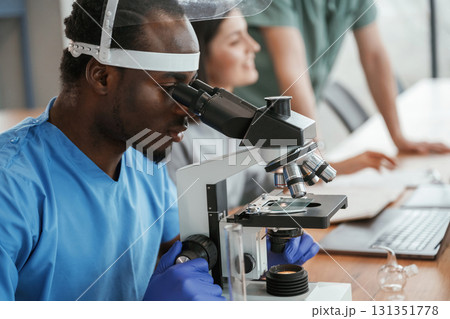 Working in a lab with test tubes and microscope. Group of doctors are together indoors 131351778