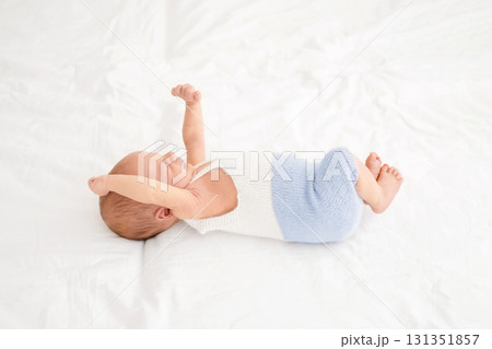 A cute newborn baby in bed wakes up pulling himself up while waking up. Strong healthy sleep of the child. 131351857