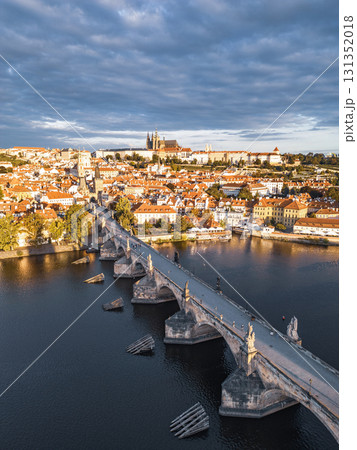 Early dawn lights up Prague's skyline, showcasing the historic Charles Bridge over the Vltava River. Prague Castle towers in the background as the city awakens in the morning. 131352018