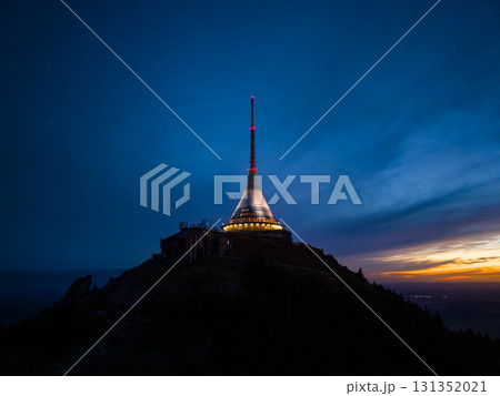 Illuminated against the evening sky, Jested Mountain Hotel stands tall in Liberec, Czechia. The modern structure glows as twilight descends, creating a serene atmosphere. 131352021